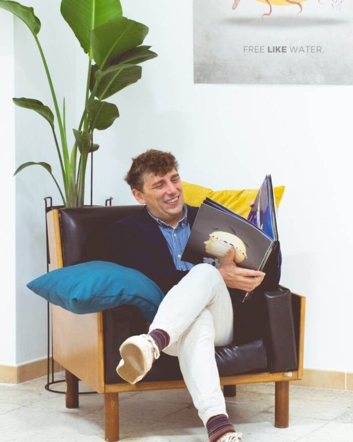 Foto del prof Genoese che sfoglia un libro seduto su una poltrona